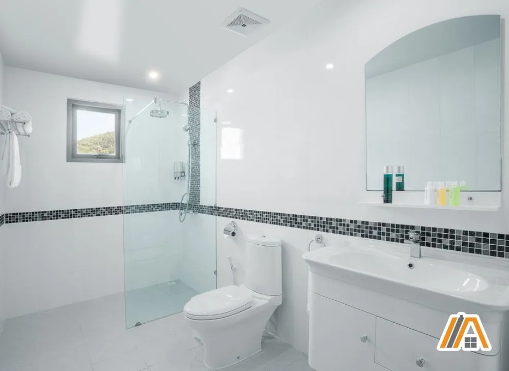 Modern white bathroom with shower, toilet and a bathroom fan above it