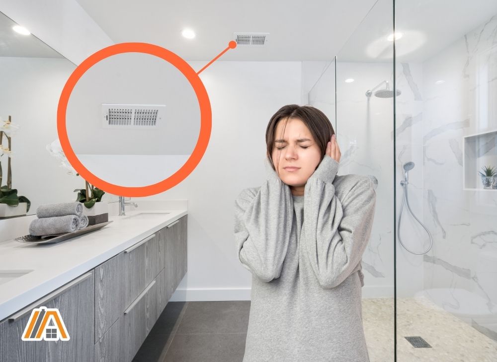 Woman covering her ears due to loud noise caused by the bathroom fan