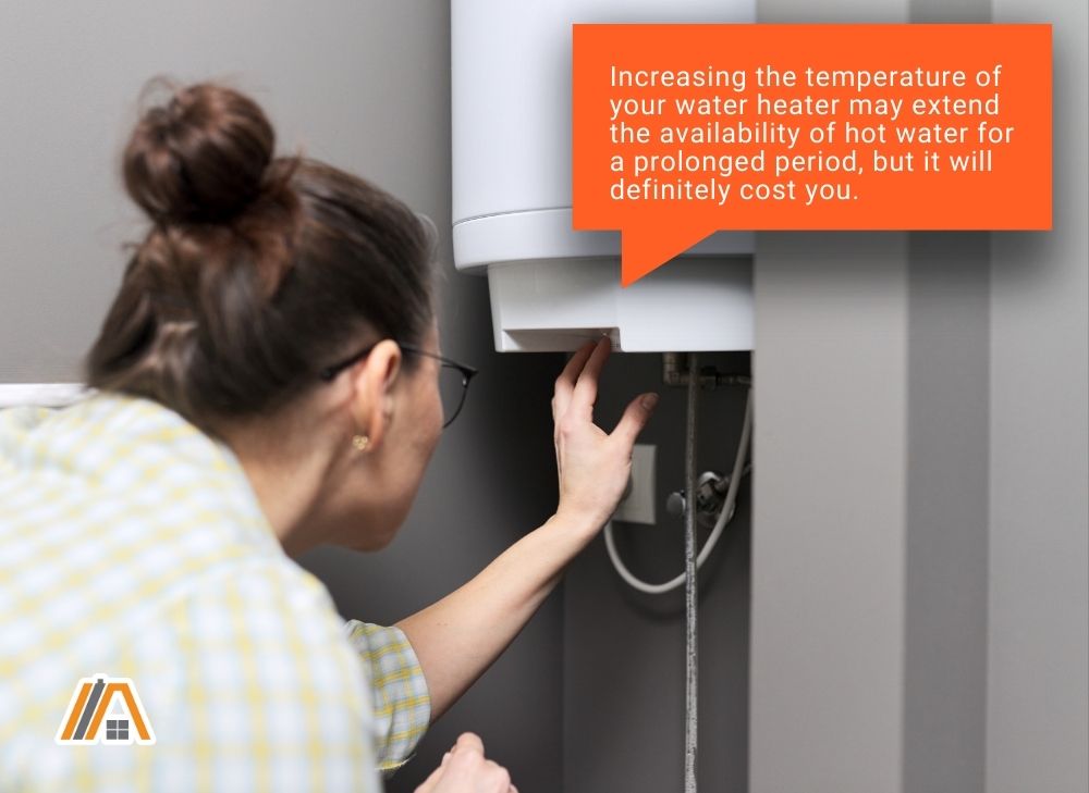 Woman increasing the temperature of the water heater, increasing temperature might extend the availability of hot water but would cost you.jpg