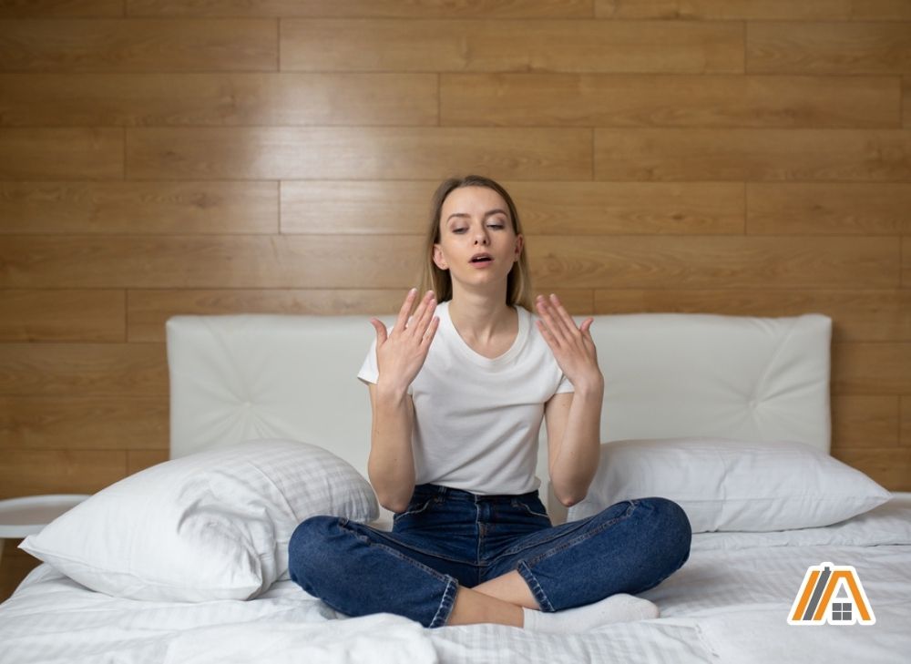 Woman wearing white shirt and jeans in bed feeling hot